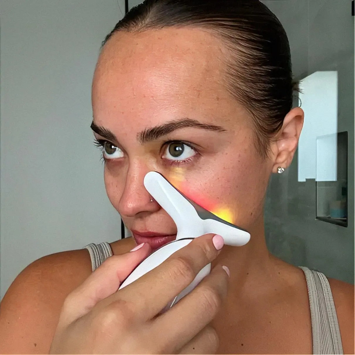 Close-up of a user sculpting her jawline and lifting sagging jowls with the Skin Revive red light anti-ageing device.