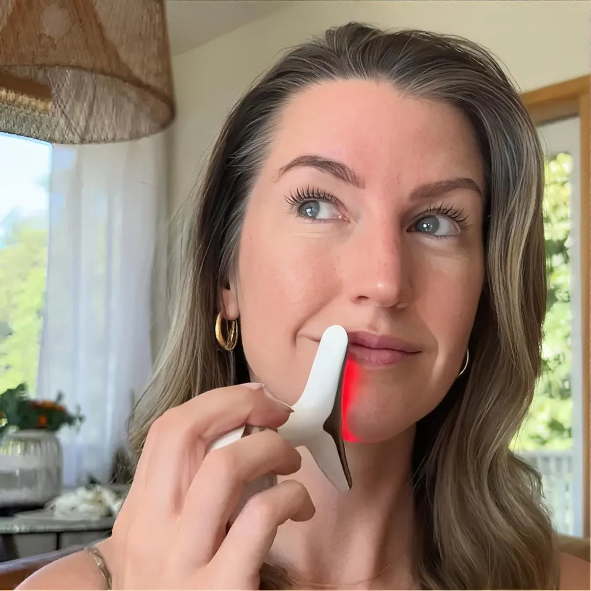 A woman successfully treating turkey neck at home using the Skin Revive red LED light massager along her jawline.
