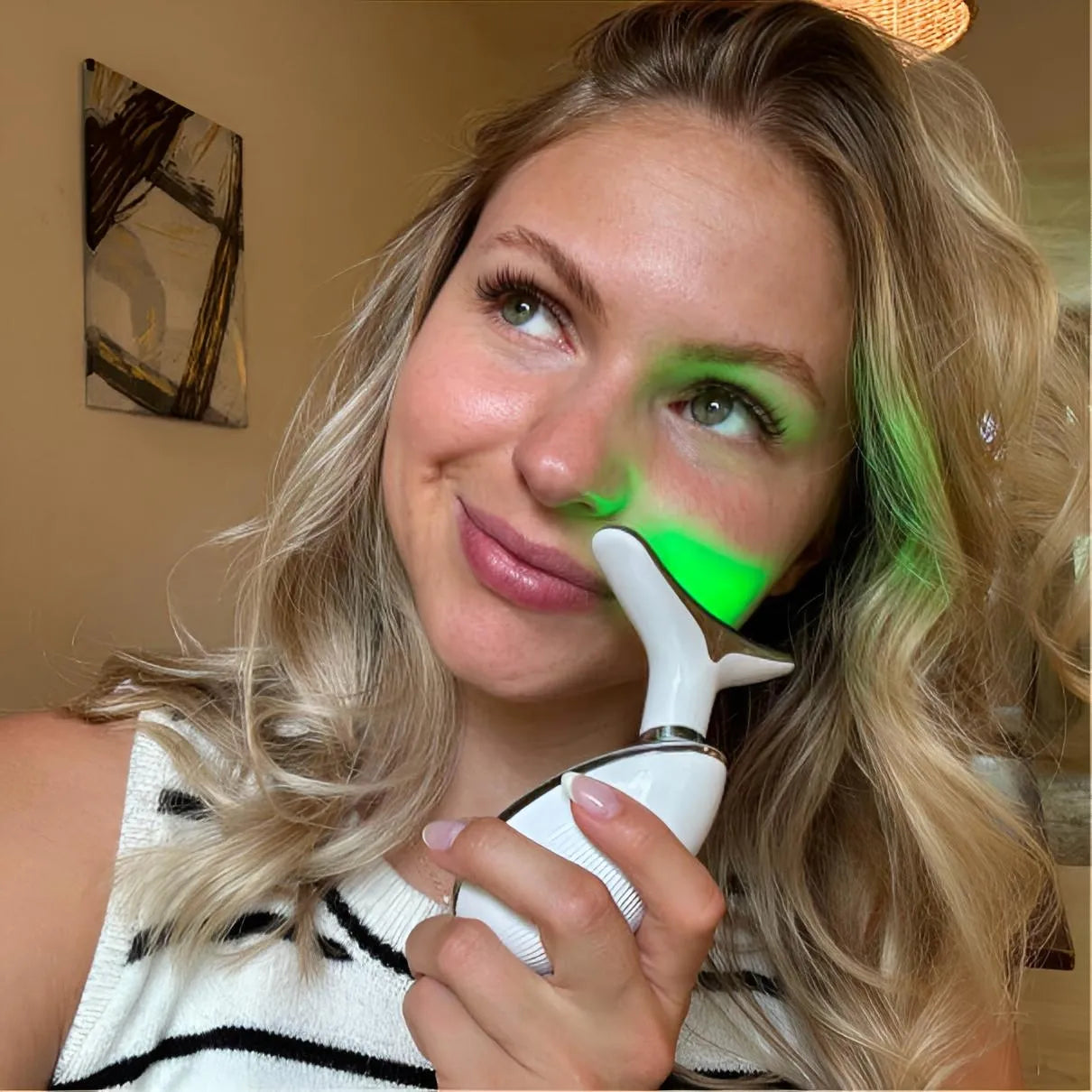 A happy customer using the Skin Revive green LED light therapy massager to balance skin tone and target pigmentation.